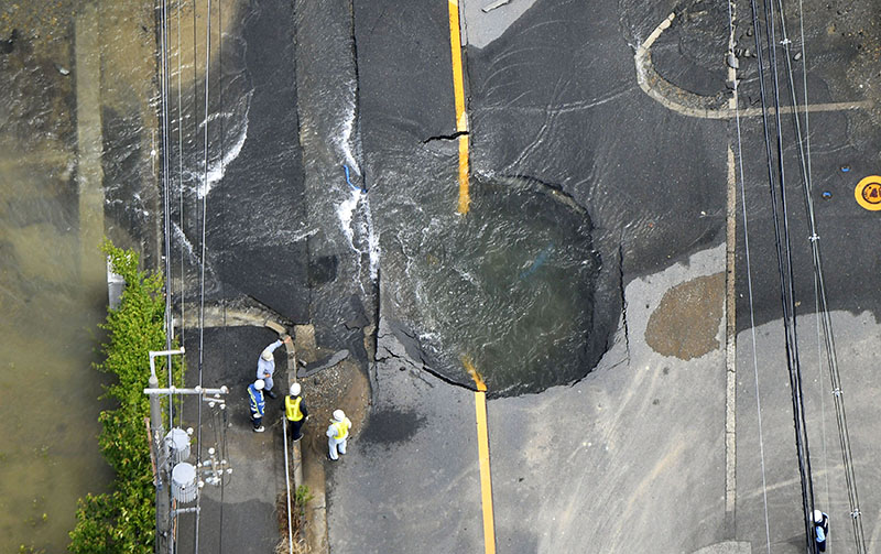 Water flows out from cracks on a road damaged by an earthquake in Takatsuki, Osaka prefecture, western Japan, on June 18, 2018. Photo: Kyodo via Reuters
