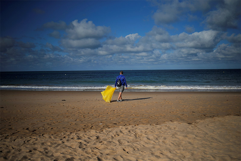 A volunteer walks as he picks up plastics, during a garbage collection, ahead of World Environment Day on La Costilla Beach, on the coast of the Atlantic Ocean in Rota, Spain, on June 2, 2018. Photo: Reuters