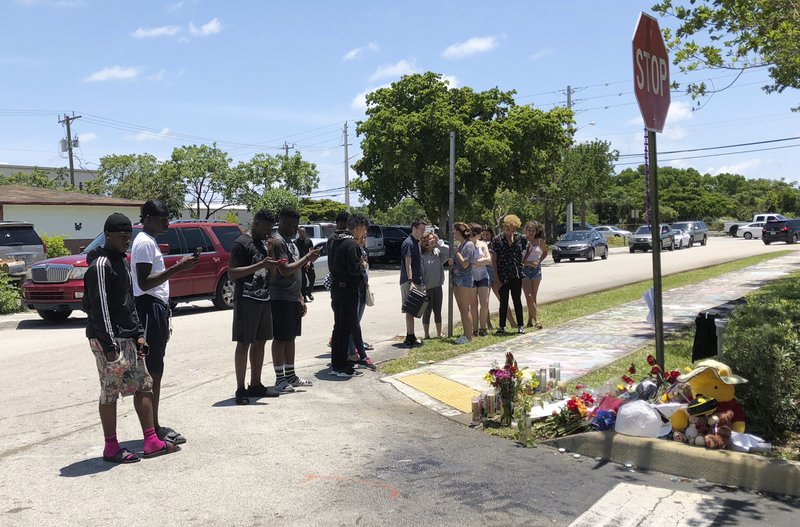 Fans and mourners of rap singer XXXTentacion pause by a memorial, Tuesday, June 19, 2018, outside Riva Motorsports in Deerfield Beach, Fla., where the troubled rapper-singer was killed the day before. 