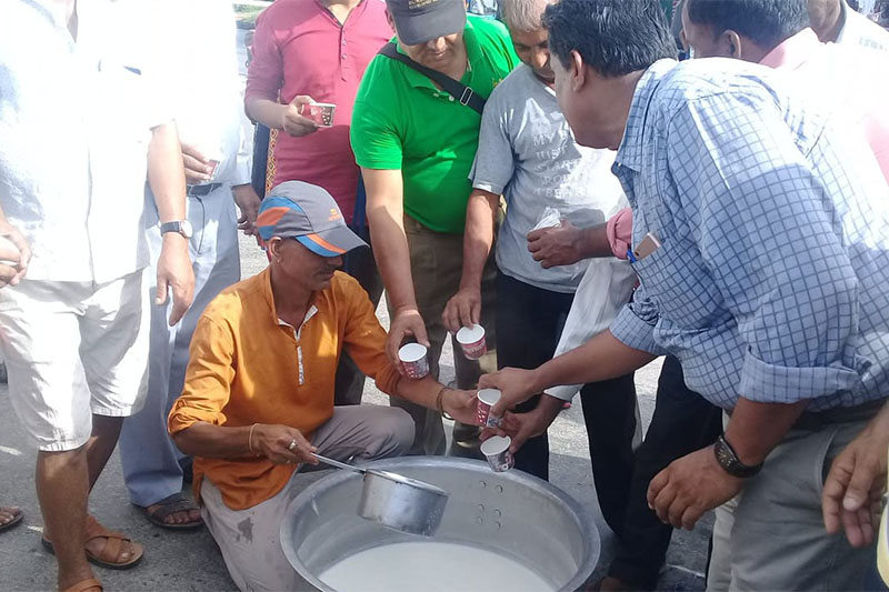 A dairy farmer hands out free milk to pedestrians at Ratnanagar in Chitwan on Monday, July 23, 2018. Photo: Tilak Ram Rimal