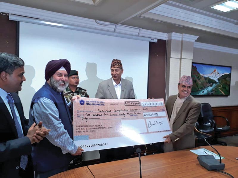 Ambassador of India to Nepal, Manjeev Singh Puri, handing over a cheque of Rs 2.1 billion to Finance Secretary Rajan Khanal, as Finance Minister Yubaraj Khatiwada looks on, in Kathmandu, on Friday, July 28, 2018. Photo: THT