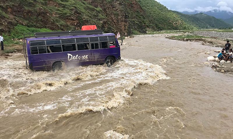 A passenger bus is seen crossing the swollen Bangad River that intersects Chhinchu-Jajarkot road section, in Jajarkot district, on Friday, August 3, 2018. As there is no bridge, vehicles have to pass through the flood during the monsoon period every year. Photo: RSS