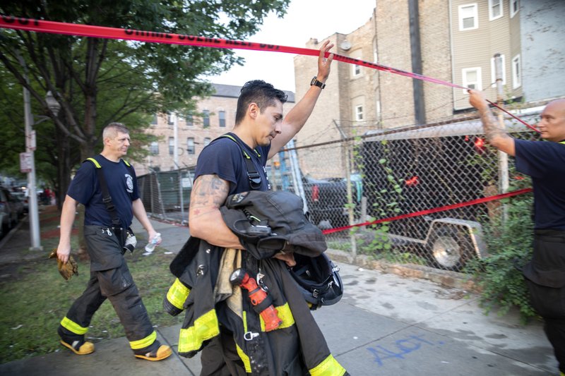 Chicago firefighters walk under tape at the scene of a fire that killed several people including multiple children on Sunday, Aug. 26, 2018, in Chicago. Photo: AP