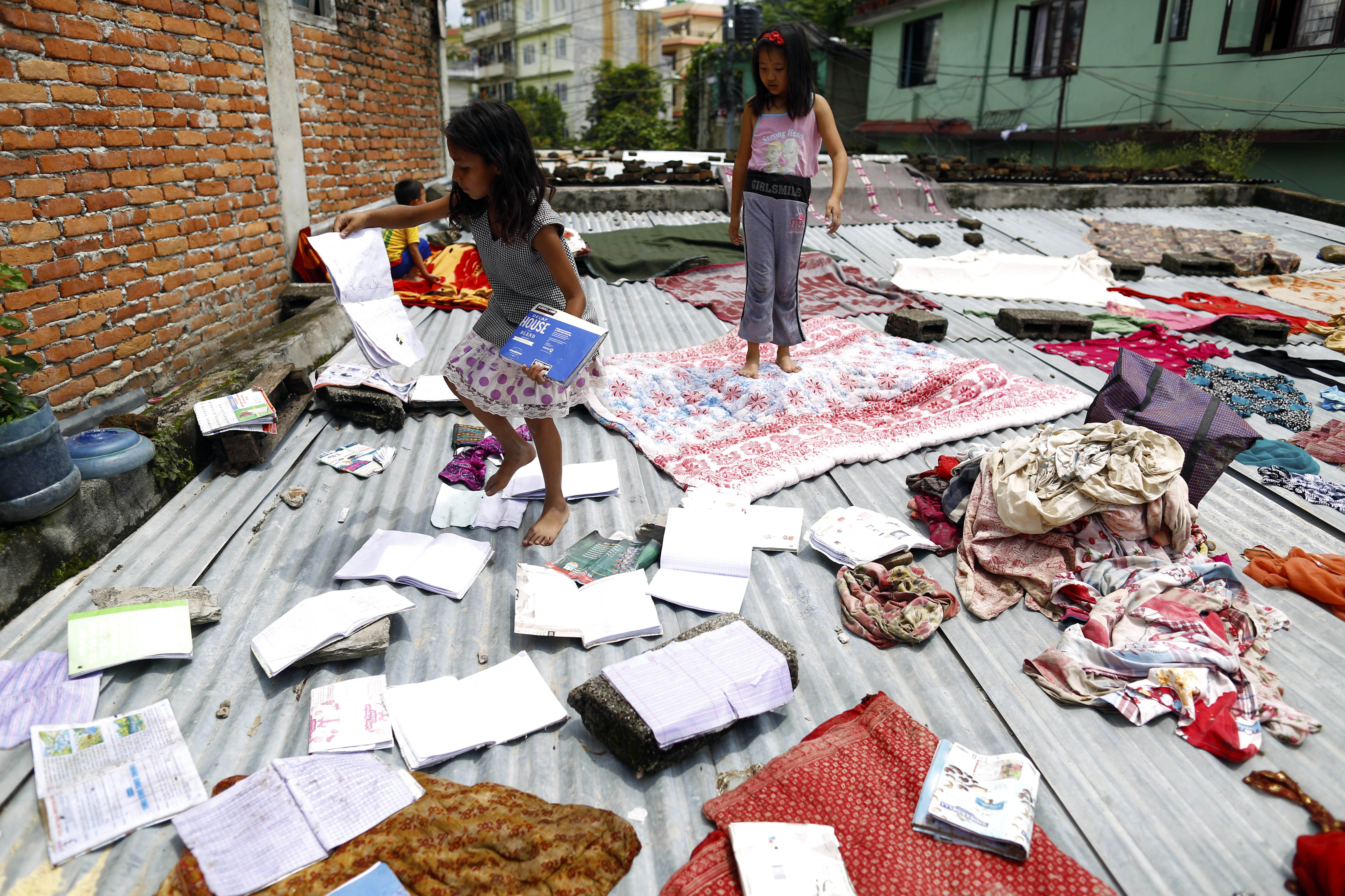 Girls dry their books on a zinc roof top  after flooded river water entered their homes in Kathmandu, on Wednesday, August 15, 2018. Photo: Skanda Gautam