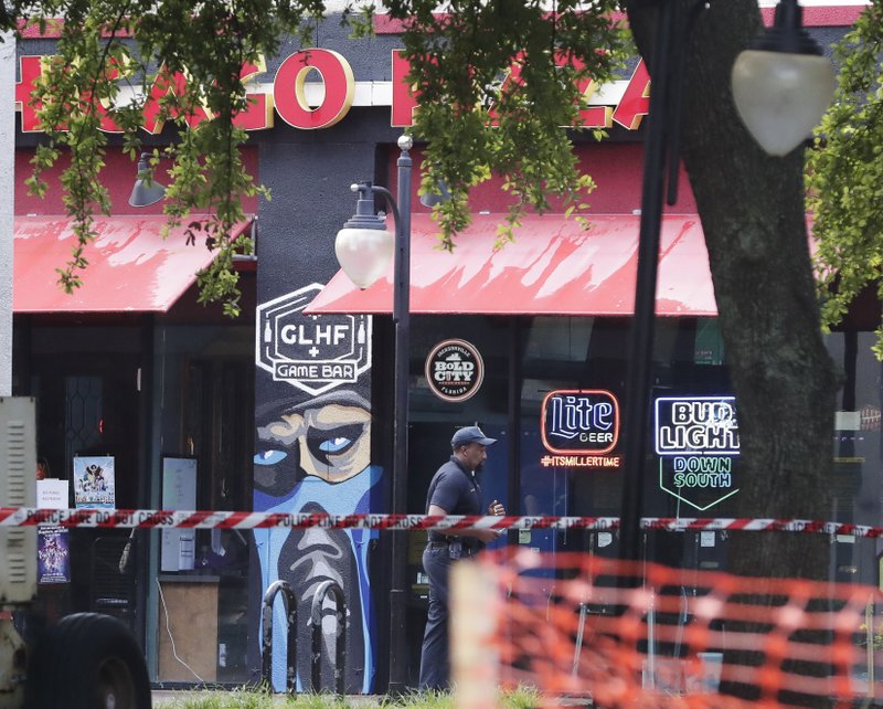 A police officer walks by the front of a Chicago Pizza and GLHF Game Bar on Monday, Aug. 27, 2018, at the scene of fatal shooting on Sunday, at The Jacksonville Landing in Jacksonville, Florida. Photo: AP