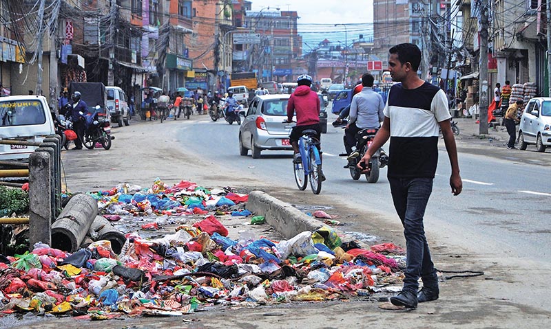 A man passing through a street littered with household garbage at Kuleshwor, in Kathmandu, on Saturday. Photo: THT