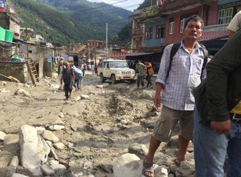 Locals walking on the road filled with mud and rocks after flood waters gushed into Bahrabise Bazaar, on Sunday, August 19, 2018. Photo: THT