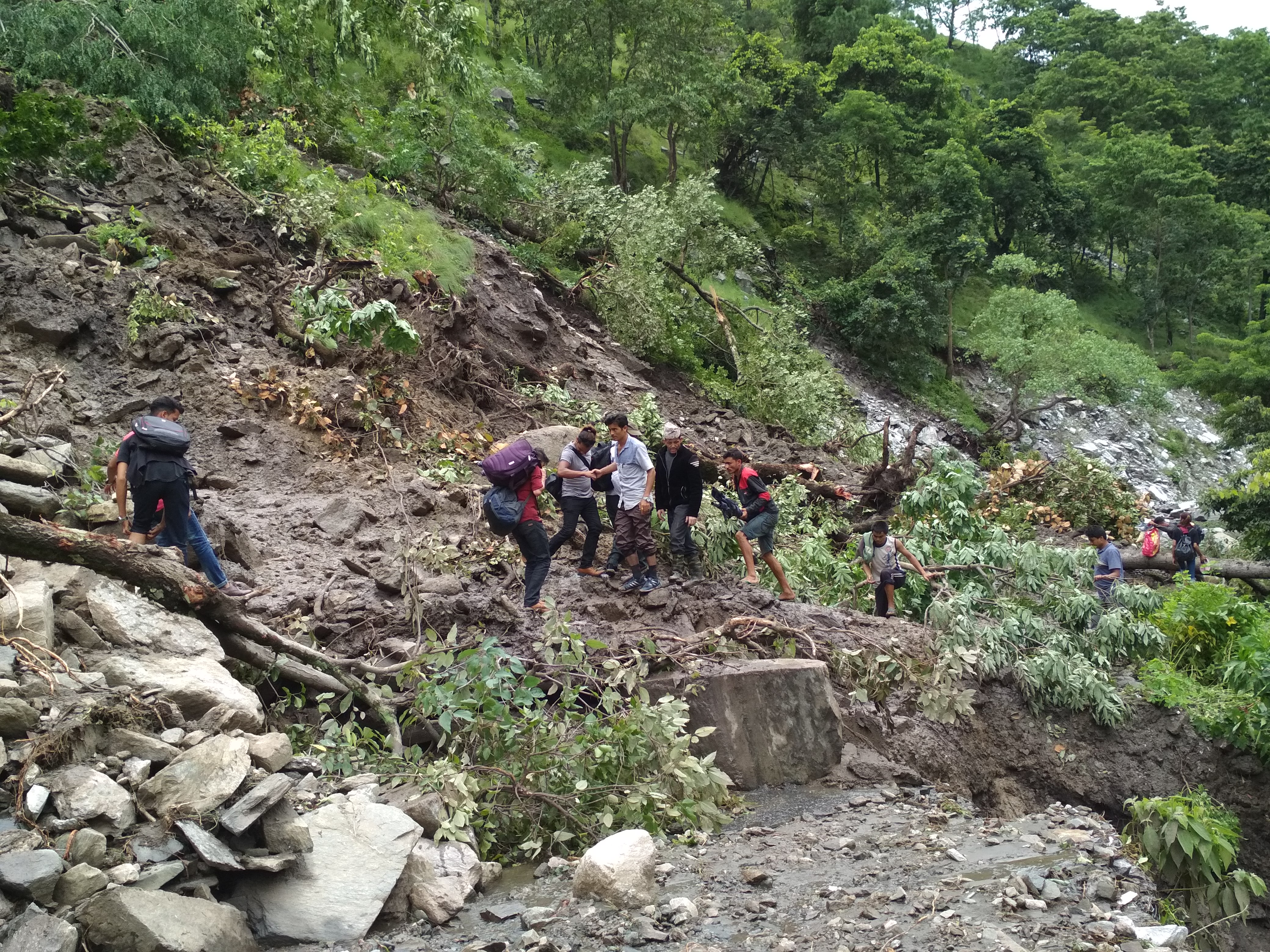 Commuters navigate their way through a stretch along the road section covered by landslip debris. Photo: Prakash Singh/THT