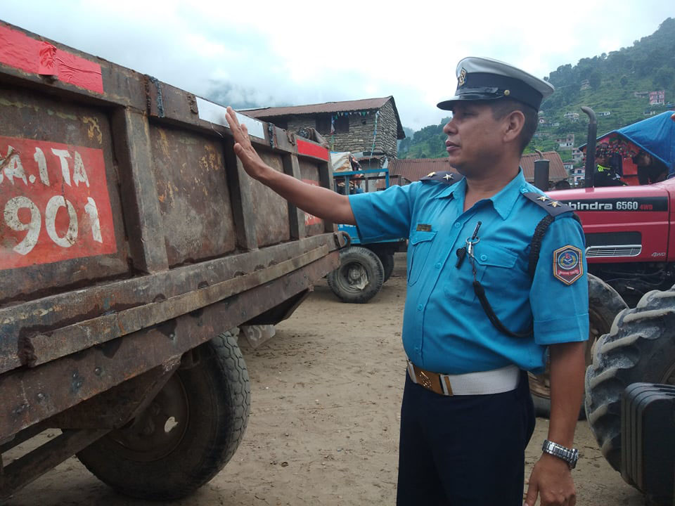 Chief of Lamjung Traffic Police, Nir Bahadur Adhikari glues reflective sticker at the rear of a tractor on Thursday, August 23, 2018. Photo: Ramji Ramji Rana/THT