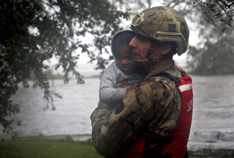 Rescue team member Sgt. Nick Muhar, from the North Carolina National Guard 1/120th battalion, evacuates a young child as the rising floodwaters from Hurricane Florence threatens his home in New Bern, N.C., on Friday, Sept. 14, 2018. Photo: APn