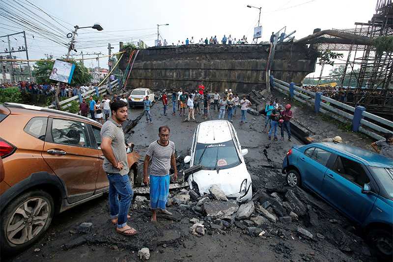 People stand next to the wreckage of vehicles at the site of a bridge that collapsed in Kolkata, India, September 4, 2018. Photo: Reuters