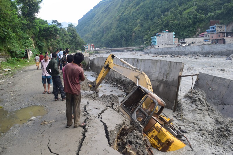 Locals look at a partially submerged excavator along the flood-ravaged retaining wall of Kali Gandaki River in Beni Bazaar, on Thursday, September 13, 2018. Photo: THT