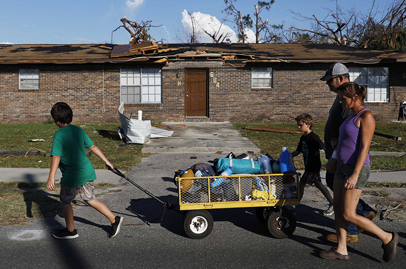 Anthony Weldon, 11, left, pulls a cart with his family's belongings as he relocates with his brother Thomas, 10, mother Dawn Clarke, right, and father Richard Coker from their uninhabitable damaged home to stay at their landlord's place in the aftermath of Hurricane Michael in Springfield, Florida, on Monday, October 15, 2018. Photo: AP