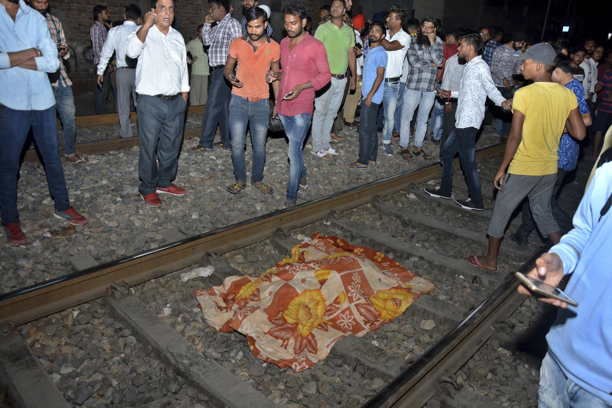 The body of a victim of a train accident lies covered in cloth on a railway track in Amritsar, India, on Friday, Oct. 19, 2018. Photo: AP