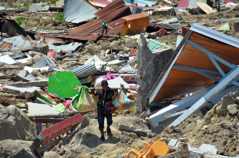 A man carry items he saved from the rubble following a major earthquake and tsunami in Palu, Central Sulawesi, Indonesia, on Monday, Oct. 1, 2018. Photo: AP