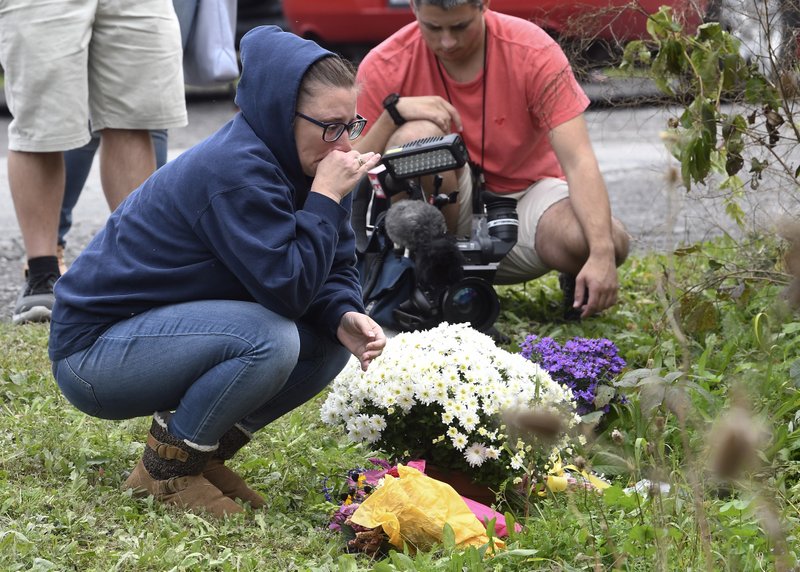 A woman kneels after placing flowers, on Sunday, Oct. 7, 2018, at the scene where 20 people died as the result of a limousine crashing into a parked and unoccupied SUV at an intersection a day earlier, in Schoharie, N.Y. Photo: AP