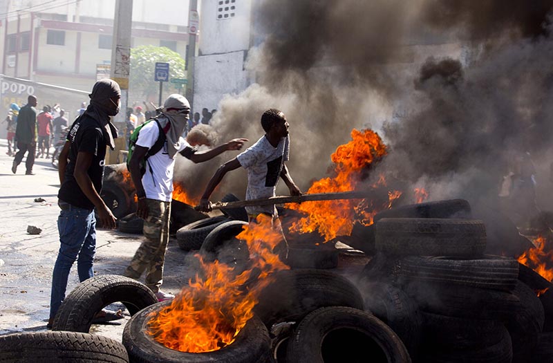 Men burn block a road with burning tires during an opposition protest demanding to know how Petro Caribe funds have been used by the current and past administrations, on the sidelines of events marking the 215th anniversary of independence Battle of Vertieres in Port-au-Prince, Haiti, Sunday, Nov. 18, 2018. Photo: AP Photo/Dieu Nalio Chery