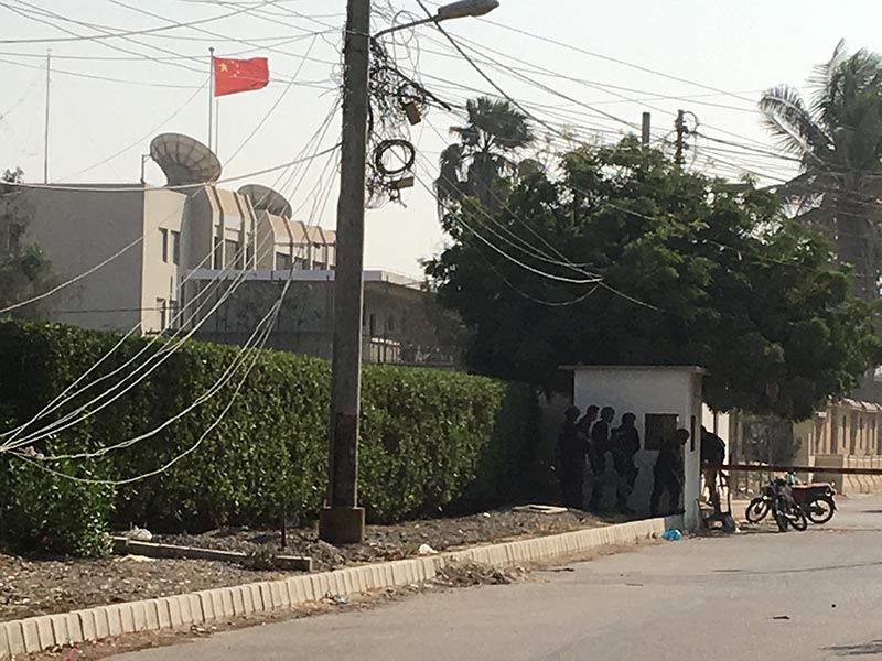 Paramilitary forces and police take cover behind a wall during an attack on the Chinese consulate, where blasts and shots are heard, in Karachi, Pakistan November 23, 2018. Photo: Reuters
