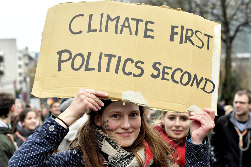 A demonstrator holds a placard which reads 'climate first, politics second' during a 'Claim the Climate' march in Brussels, on Sunday, December 02, 2018. Photo: AP
