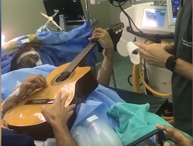 Jazz Guitarist Manzini plays guitar while at the treatment table for a brain surgery. Photo :Youtube
