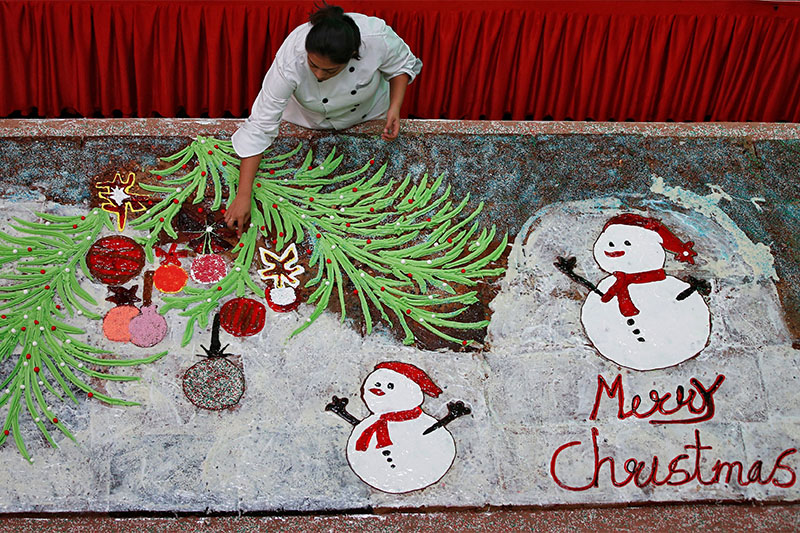 A chef applies finishing touches to a 56-feet-long Christmas plum cake inside a shopping mall in Ahmedabad, India, on December 24, 2018. Photo: Reuters