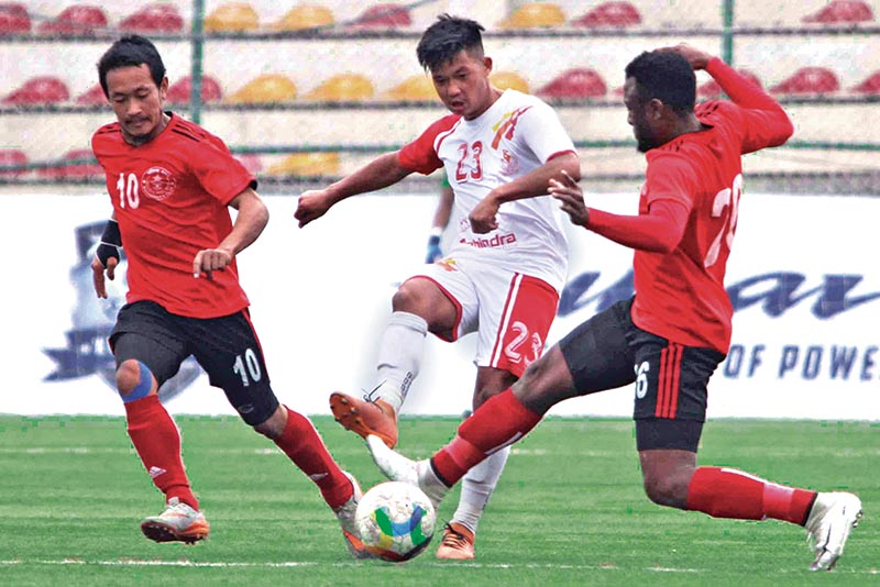 Nepal APF Clubu2019s Aashish Lama (centre) shoots the ball past Machhindra FC players during their Pulsar Martyrs Memorial A Division League match in Lalitpur on Tuesday. Photo: Udipt Singh Chhetry/THT