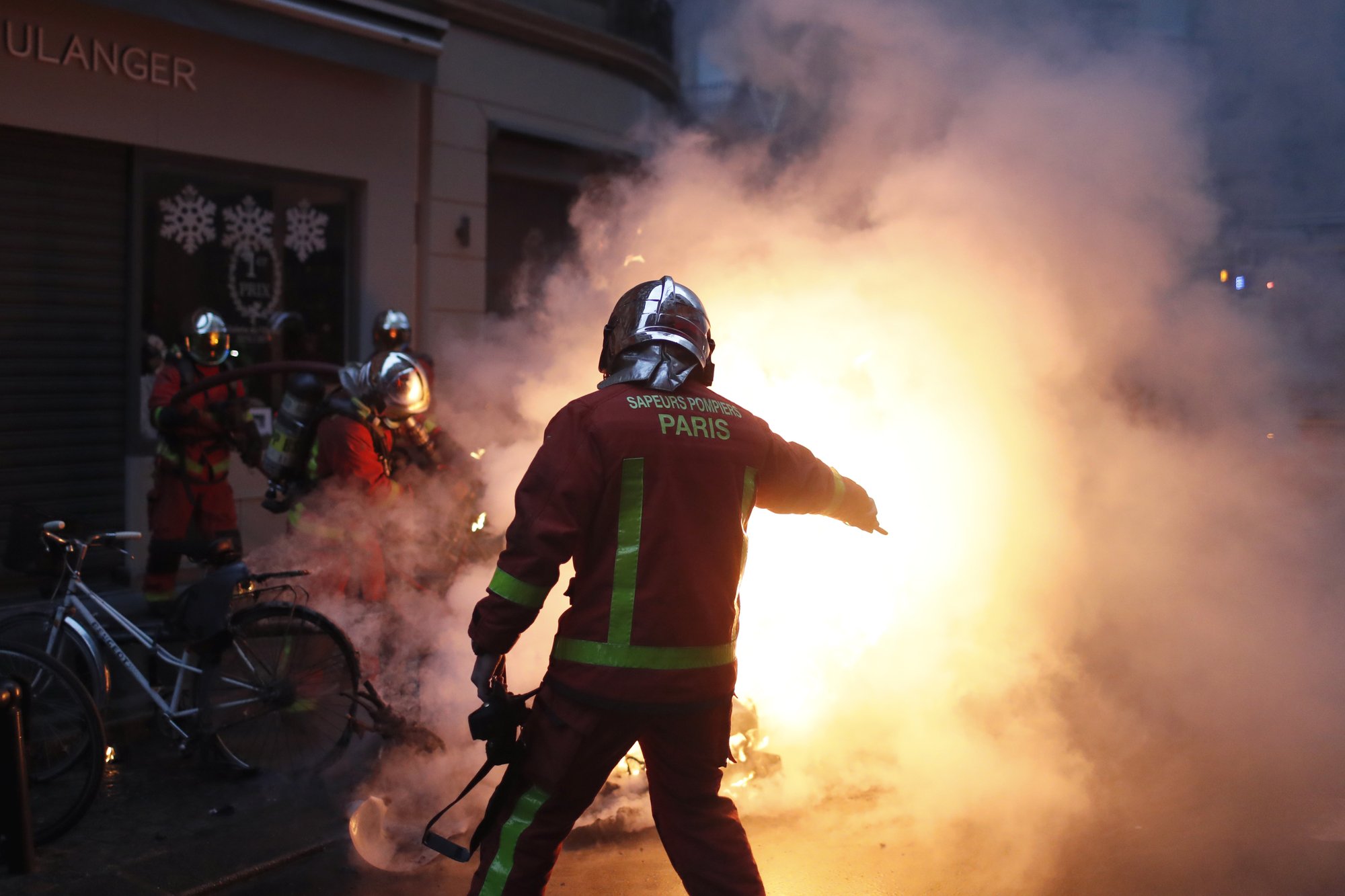Firefighters try to extinguished a car set on fire by demonstrators during clashes with riot police, in Paris, France, on Saturday, Dec. 8, 2018. Photo: AP