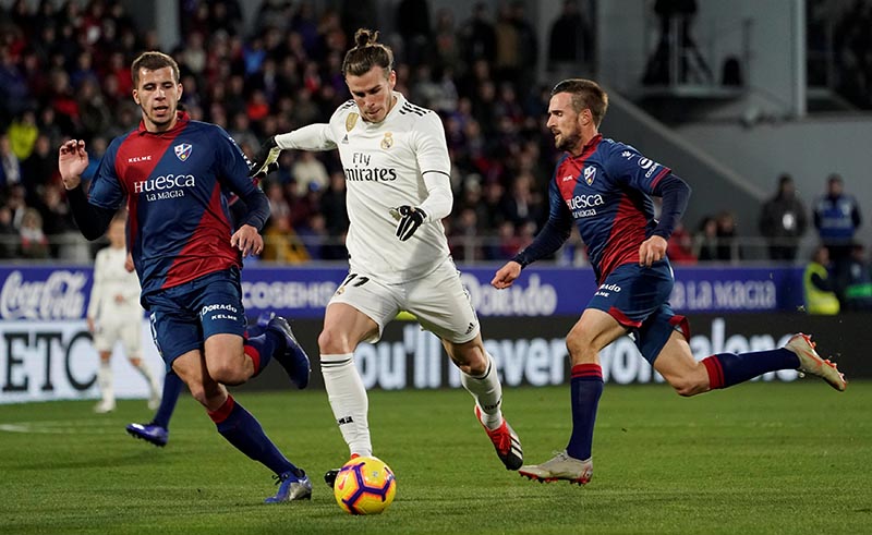 Real Madrid's Gareth Bale in action with Huesca's Christian Rivera and Jorge Miramon during the  La Liga Santander match between SD Huesca and Real Madrid, at Estadio El Alcoraz, in Huesca, Spain, on December 9, 2018.