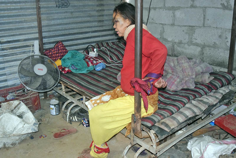 Sunita Bote sits on a bed as she is tied at both her hands and feet at a garage in Dhading district. Photo: Keshav Adhikari/THT