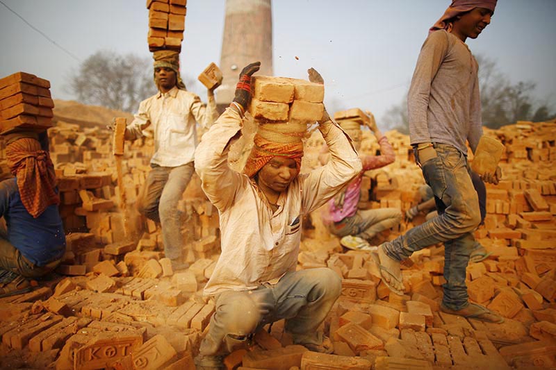 Indian migrant laborers carry stacked bricks on their head at a brick kiln in Bhaktapur, on Thursday, January 10, 2019. Photo: Skanda Gautam/THT