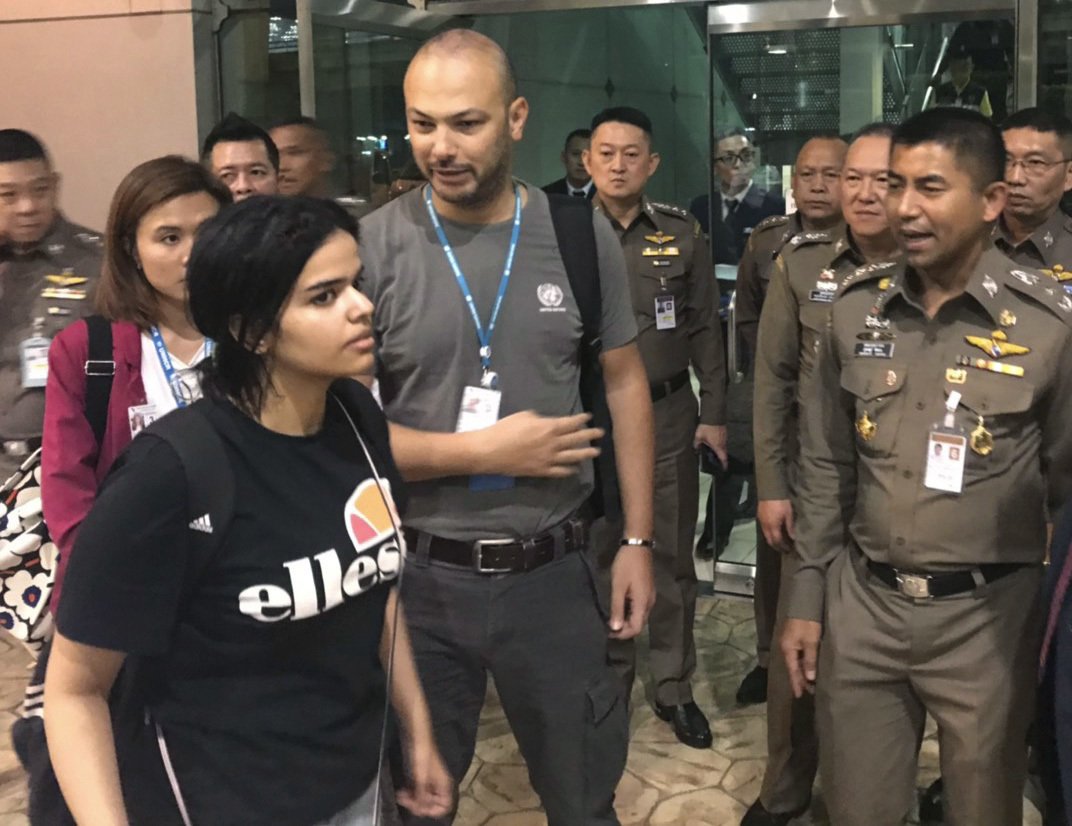 In this photo released by the Immigration Bureau, Saudi woman Rahaf Mohammed Alqunun, foreground walks by Chief of Immigration Police Maj. Gen. Surachate Hakparn, right, before leaving the Suvarnabhumi Airport in Bangkok on Monday, Jan. 7, 2019.