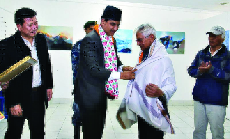 Gandaki Province Industry Minister Bikash Lamsal honouring artist Durga Baral at a conservation art exhibition, in Pokhara, on Monday. Photo: THT