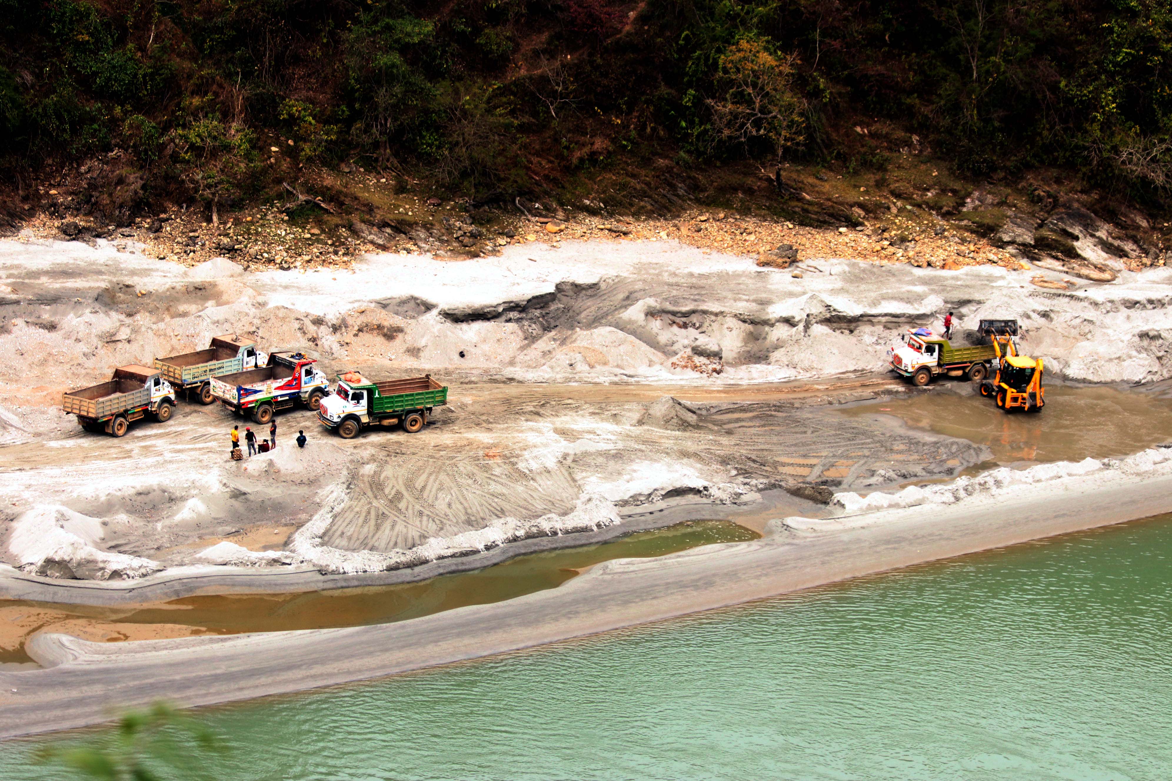 An excavator loads sand into a truck while other trucks queue at an illegal river mining site at Rising Rural Municipality along the Kali Gandaki river in Tanahun on Monday, February 18, 2019. Photo: Madan Wagle/THT
