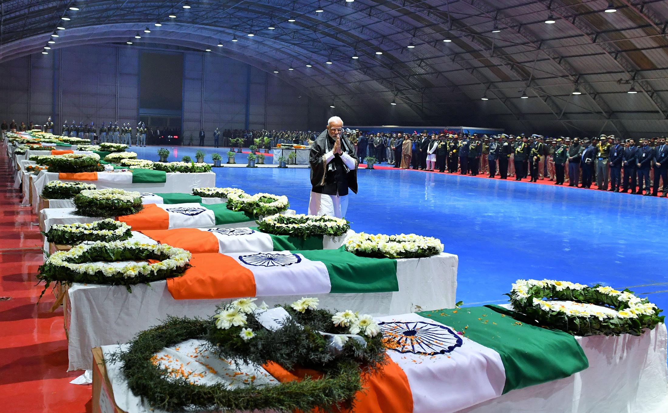 India's Prime Minister Narendra Modi pays tribute as he walks next to the coffins containing the remains of Central Reserve Police Force (CRPF) personnel who were killed after a suicide bomber rammed a car into a bus carrying them in south Kashmir on Thursday, at Palam airport in New Delhi, India, February 15, 2019. Photo: India's Press Information Bureau/Handout via REUTERS