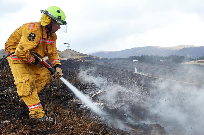 Firefighter Lieutenant Oli Barnfather of the New Zealand Army fights an underground hotspot on the Port Hills of Christchurch, New Zealand, February 6, 2019. Photo: New Zealand Defence Force/Dillon Anderson/Handout via Reuters