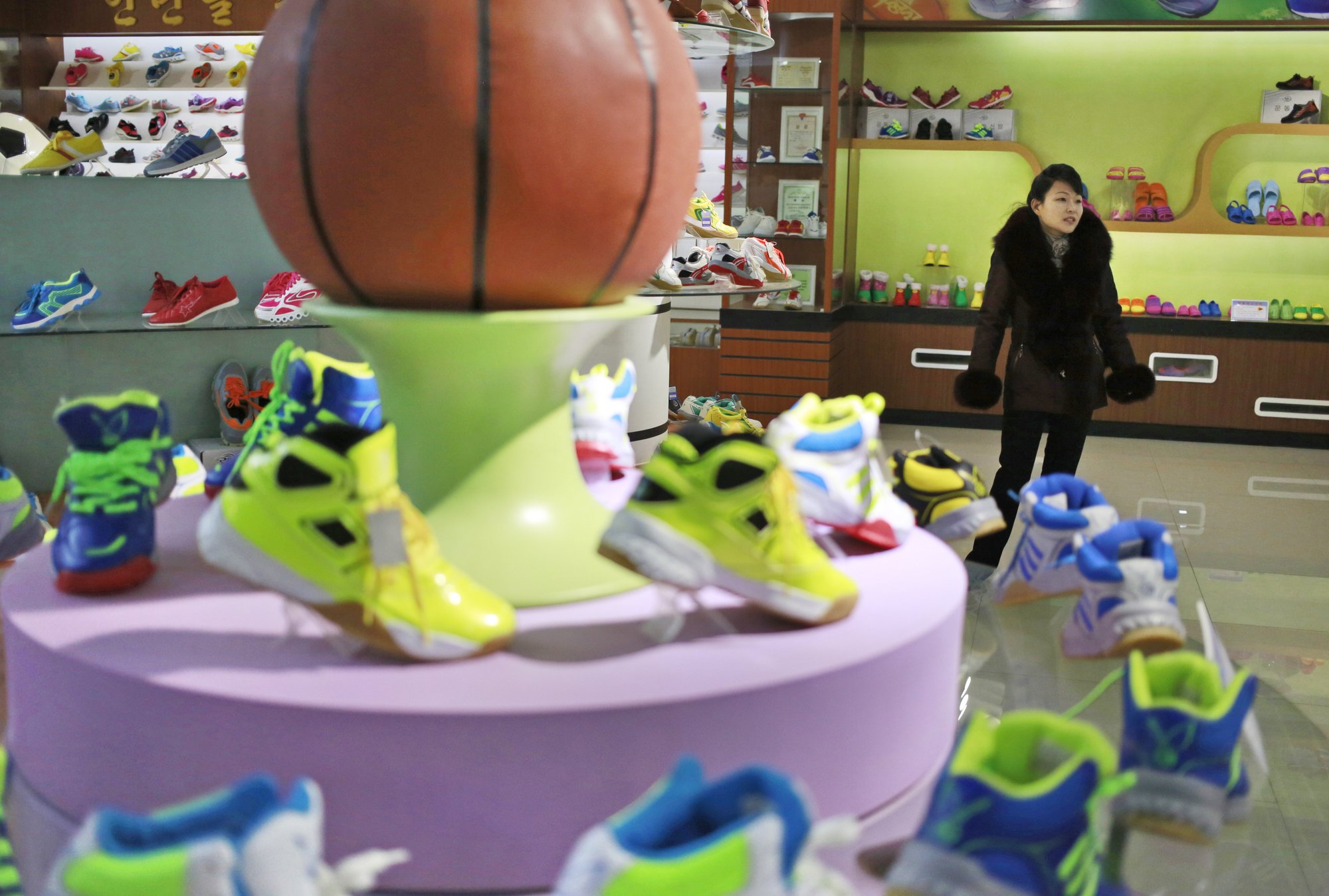 In this Friday, Feb. 1, 2019, photo, a guide stands near a basketball shoe display in a product exhibition room at the Ryuwon Shoe Factory that specializes in sports footwear, in Pyongyang, North Korea. Photo: AP