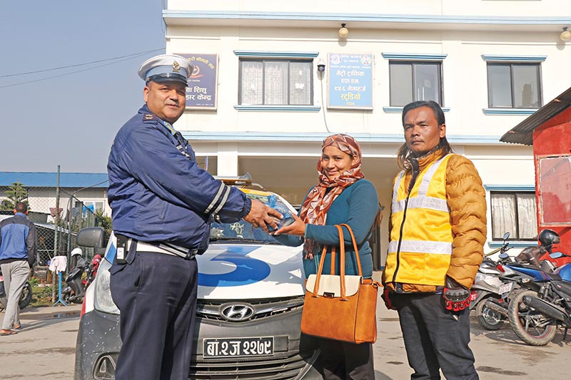 A traffic policeman handing over valuables returned by a taxi driver to the owner, in Kathmandu, on Wednesday, February 20, 2019. Photo: THT