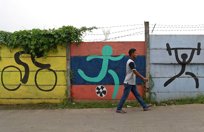 FILE - A man walks past sports murals originally painted on a wall as promotional tools for the 2018 Asian Games in Jakarta, Indonesia, as on Tuesday, February 19, 2019. Photo: AP