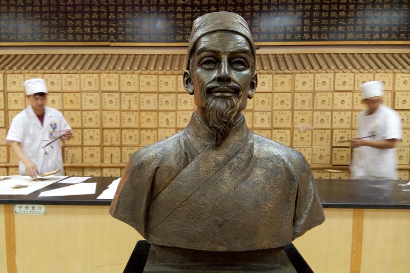 Workers weigh herbs behind a bust portraying Chinese herbalist Li Shizhen of the Ming dynasty, at a traditional Chinese medicine store in Beijing, China June 7, 2015. Photo: Reuters/File