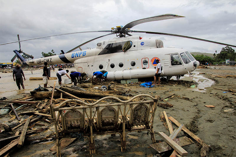 People stand near a helicopter shifted after flash floods in Sentani, Papua, Indonesia, March 17, 2019 in this photo taken by Antara Foto. Photo: Reuters