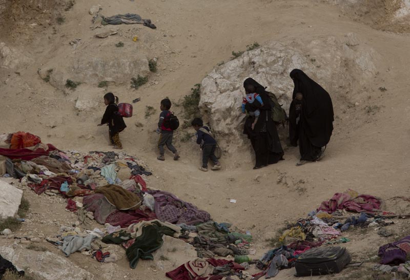 Women and their children who left the besieged Islamic State-held village of Baghouz, Syria, scramble over a rocky hillside to be checked by US-backed Syrian Democratic Forces on March 14, 2019. Photo: AP/File