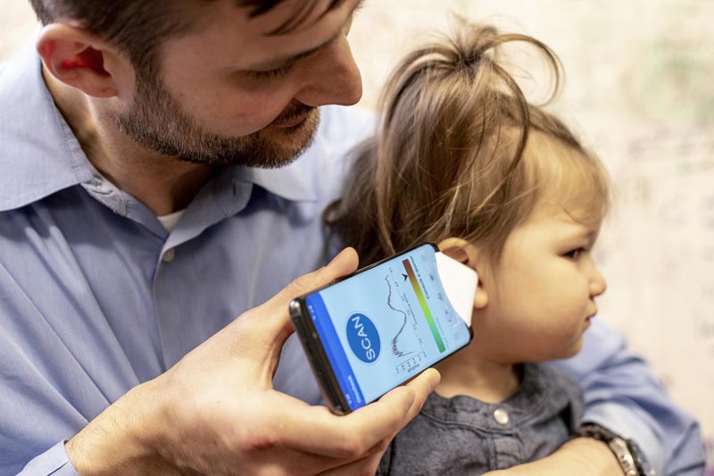 In this undated photo provided by the University of Washington in May 2019, Dr. Randall Bly uses a uses a phone app and a paper funnel to focus the sound, to check his daughter for an ear infection, at the UW School of Medicine in Seattle. Bly and other researchers at the school have developed the system to u0093hearu0094 a warning sign of ear infections _ fluid build-up behind the eardrum. Photo: AP