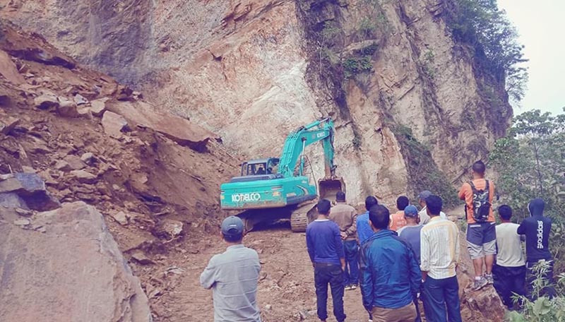 People watch excavator removing landslide debris fallen from Numnatim Bhir on Leguwa-Bhojpur road, in Bhaisipankha of Bhojpur Municipality-10, in Bhojpur district, on Wednesday, May 22, 2019. Photo: Niroj Koirala/ THT