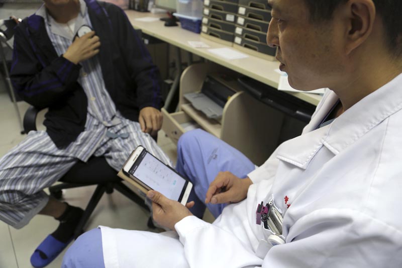 Dr Li Dianyou uses a tablet computer to adjust the settings of a deep brain stimulation device implanted in the brain of a methamphetamine user named Yan, left, on Monday, October 29, 2018, at Ruijin Hospital in Shanghai, China. Photo: AP