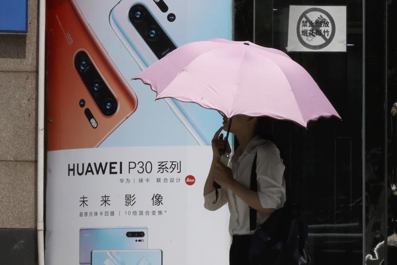A woman walks past advertisement for Huawei smartphones in Beijing on Thursday, May 16, 2019. Photo: AP