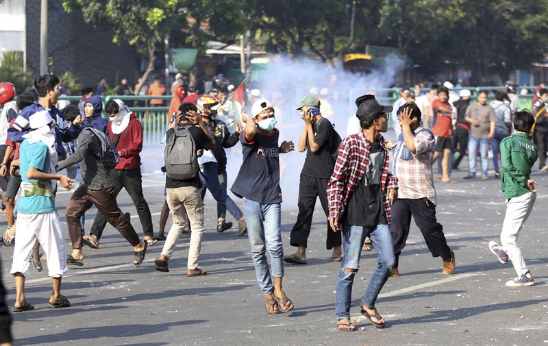 Supporters of Indonesian presidential candidate Prabowo Subianto run from smoke of tear gas fired by police officers in Jakarta, Indonesia, Wednesday, May 22, 2019. Photo: AP