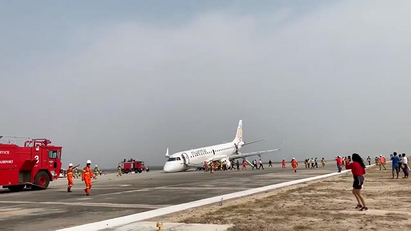 An evacuated passenger records on her phone as firefighters attend to the scene after Myanmar National Airlines flight UB103 landed without a front wheel at Mandalay International Airport in Tada-U, Myanmar, on May 12, 2019 in this still image taken from social media video. Photo: Nay Min via Reuters