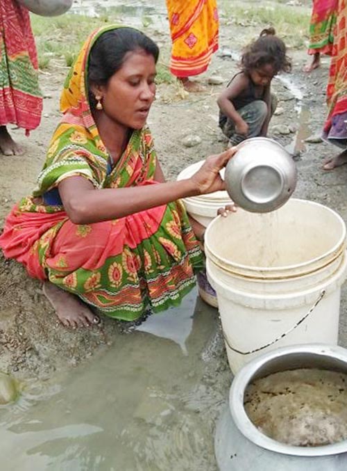 A woman from the Musahar community filling a bucket with contaminated water from Bataha Khola in Mirchaiya Municipality, Siraha, on Tuesday, May 28, 2019. Photo: THT