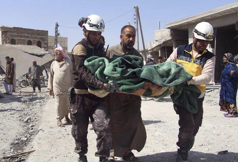 The White Helmets, shows members of the Syrian Civil Defense workers carrying a victim after a deadly airstrike hit a market killing several people in the village of Ras el-Ain, in the northwestern province of Idlib, Syria, Tuesday, May 7, 2019. Photo: Syrian Civil Defense White Helmets via AP