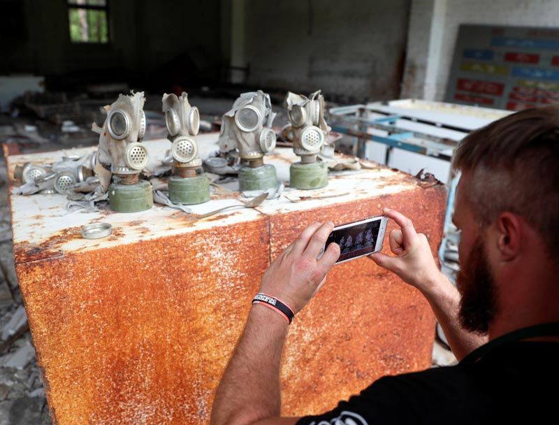 A visitor takes a picture of gas masks at a former base of the Soviet army, near the Chernobyl Nuclear Power Plant, Ukraine June 2, 2019. Picture taken June 2, 2019. Photo: Reuters